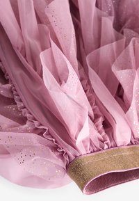 Rosa Tüllstoff mit goldenen Punkten, mit rüschierten Kanten und einem strukturierten goldenen Taillenbund. Weiches und voluminöses Design.