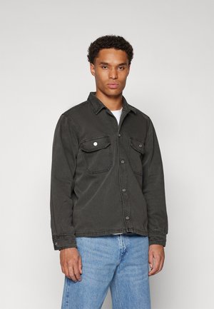 Dark gray denim jacket with two front pockets, button closure, and long sleeves. Paired with light blue jeans.
