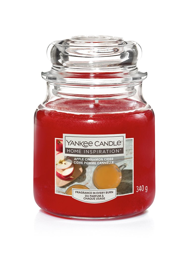 Candela in vaso di vetro rosso etichettata "Sidro di mele e cannella", con coperchio trasparente, un'etichetta con immagini di mele e sidro, e un peso di 340 g.