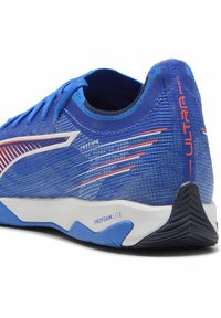Niebieski but sportowy z teksturowanym, syntetycznym wierzchem, z pomarańczowymi akcentami i białą podeszwą środkową oznaczoną "PROFOAM LITE". Tył ma charakterystyczny wzór bieżnika.