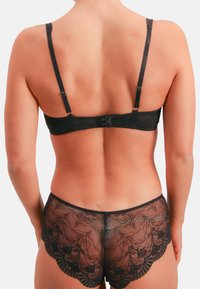 Schwarzer Spitzen-BH und passende Pantys mit floralem Muster. Verstellbare Träger, gezackte Kanten und feine Netzstruktur.