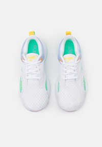 Un paio di scarpe da corsa Nike bianche con solette turchesi, logo giallo e linguette arancioni, viste dall'alto su uno sfondo bianco.