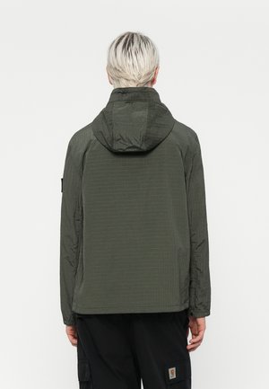 Jachetă ușoară de culoare verde închis, cu glugă. Țesătură texturată cu aspect crăpat, cusături vizibile și manșete elastice. Design simplu și funcțional.