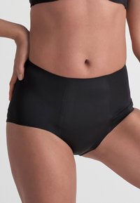 Högmidjade svarta underkläder gjorda av slätt material, med en sömlös design utan synliga sömmar och en kroppsnära passform.