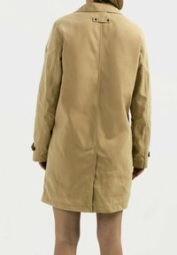 Béžový trenčkot vyrobený z hladkého materiálu, s límečkem, dlouhými rukávy a knoflíkovými detaily na manžetách a vzadu.