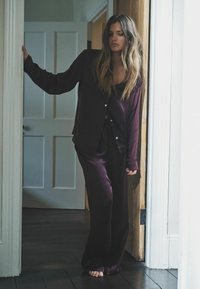 Conjunto de pijama de seda burdeos que incluye una camisa de botones de manga larga y pantalones holgados, con una textura suave y un diseño minimalista.