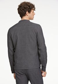 Texturerad, svartvit rutig långärmad skjorta med rak skärning, minimalistisk krage och knappade ärmslut, bärs med matchande byxor.