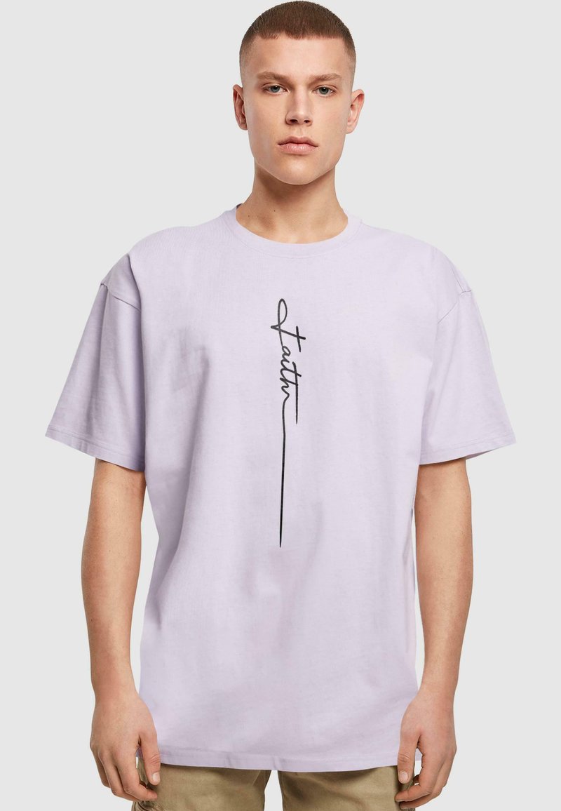 Lys lilla bomulds-t-shirt med en afslappet pasform, der har et sort håndskrevet "Faith" design i midten. Enkelt, korte ærmer.