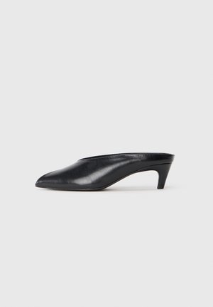 Schwarze Leder-Mules mit einer spitzen Zehenform, niedrigem Absatz und glatter Textur. Minimalistisches Design ohne sichtbare Beschläge oder Muster.