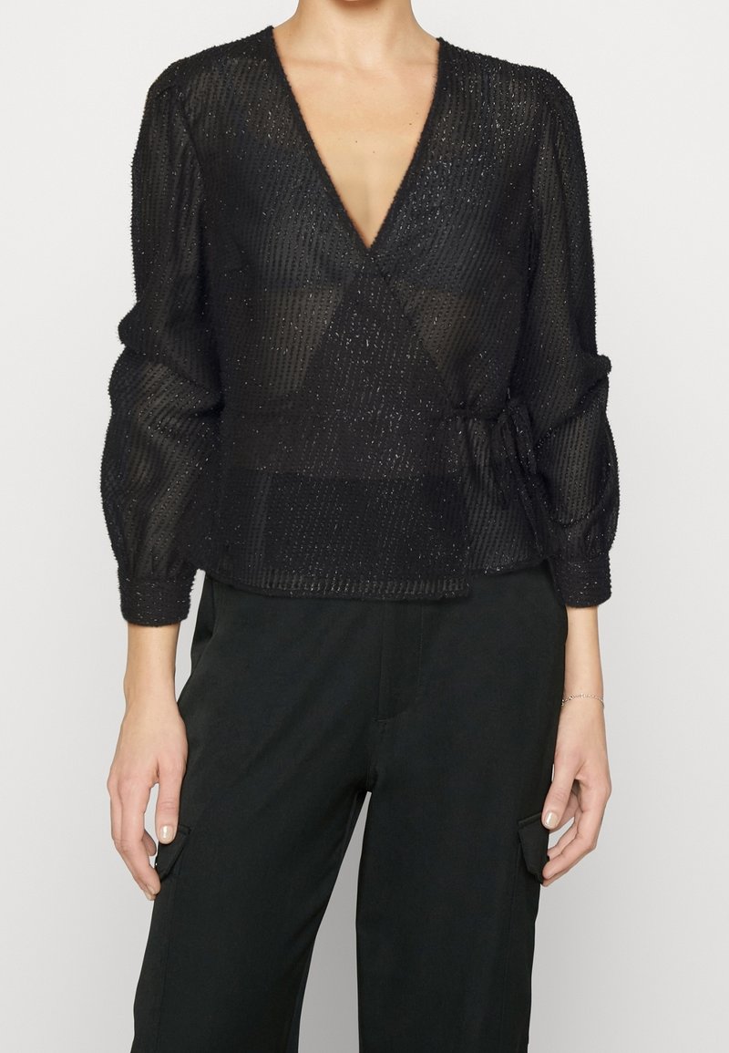 Blusa nera avvolgente con lunghe maniche a sbuffo, realizzata in un tessuto trasparente e testurizzato con sottili strisce verticali e un nodo in vita.
