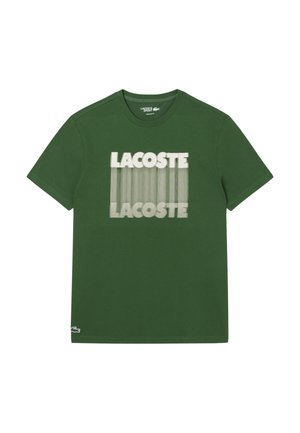 Camiseta de algodón verde con el logo impreso "LACOSTE" en blanco y un patrón de líneas, cuello redondo y mangas cortas.