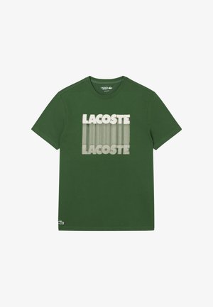 Camiseta de algodón verde con el logo impreso "LACOSTE" en blanco y un patrón de líneas, cuello redondo y mangas cortas.