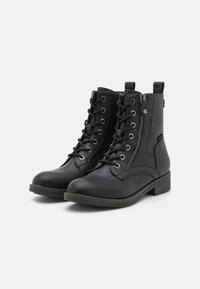 Botines de cuero negro hasta el tobillo con cierre de cordones en la parte delantera, cremallera lateral y acabado texturizado. Tacón bajo y detalles de costura sutiles.