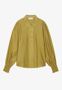 Blusa verde senape con colletto classico, chiusura anteriore con bottoni e maniche lunghe. Presenta polsini arricciati e una finitura in tessuto strutturato.