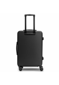 Maleta rígida negra con un mango retráctil, dos ruedas laterales y una superficie texturizada. Presenta un diseño rectangular minimalista.