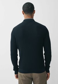 Pullover in maglina a coste navy con colletto alto e maniche lunghe, caratterizzato da una texture liscia e da un design aderente, visto da dietro.