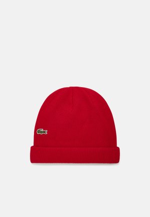 Gorro de punto acanalado rojo con vuelta y un pequeño logo verde de Lacoste en el lado. Textura suave y forma ajustada.