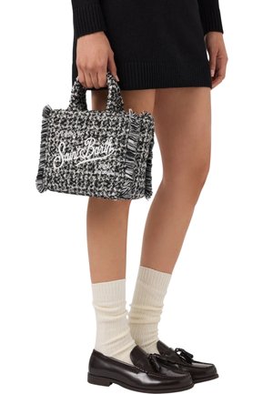 Borsa in tessuto intrecciato bianco e nero con dettagli frangiati, dotata di un logo stampato bianco. Manici corti per un facile trasporto.