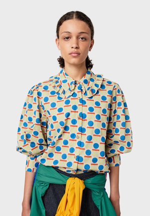 Colorful puff-sleeve shirt in yellow with blue circles and red lines. Features a large ruffled collar and button front.