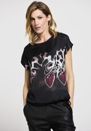 Schwarzes T-Shirt mit kurzen Ärmeln, das ein Leopardenmuster und rote Herzgrafiken zeigt. Es besteht aus glattem Stoff und hat eine lässige Passform.