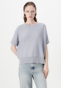 Lyseblå kortermet topp med løs passform og ribbet kant. Stoffet ser mykt ut med en jevn tekstur. Bært sammen med lyseblå denimjeans.