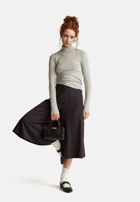 Szary sweter z golfem, czarna spódnica o szerokich nogawkach, białe skarpetki z prążkami, czarne mokasyny z paskami oraz mała czarna torebka.