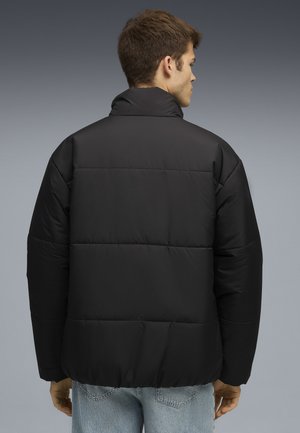 Zwarte pufferjack met hoge kraag en gestikt ontwerp. Gemaakt van soepel fabric, met een losse pasvorm en elastische zoom.
