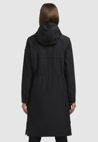 Pardoseală lungă neagră cu glugă, talie strânsă și manșete cu capse. Textură netedă, design minimalist, cu fermoare laterale pentru ușurință.