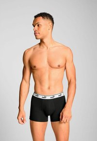 Black boxer briefs with a white elastic waistband featuring the Puma logo. The fabric appears smooth and form-fitting.