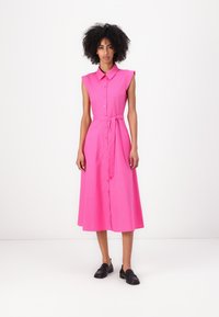 Rochie roz, fără mâneci, cu nasturi și guler, cu un cordon la talie și fustă până la genunchi. Material neted, cu o finisare de culoare solidă. Se poartă loafers negri.