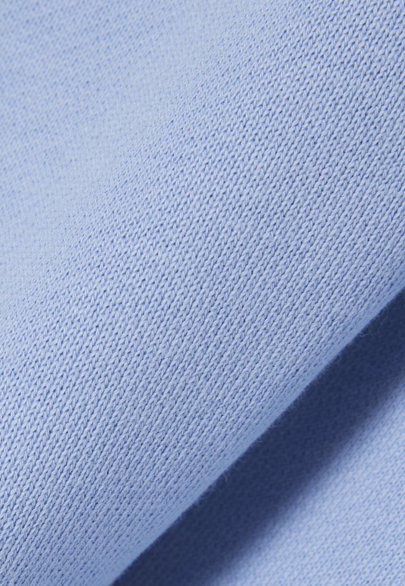 Tessuto lavorato a maglia di azzurro chiaro con punti fini e uniformemente distanziati che creano una texture morbida e liscia con leggere pieghe sovrapposte.
