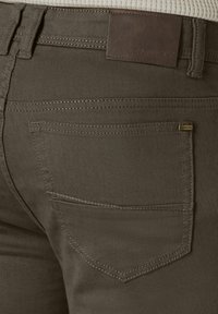 Olive green pants with a textured fabric. Features include a brown leather patch on the waistband and stitched back pockets with a subtle design.