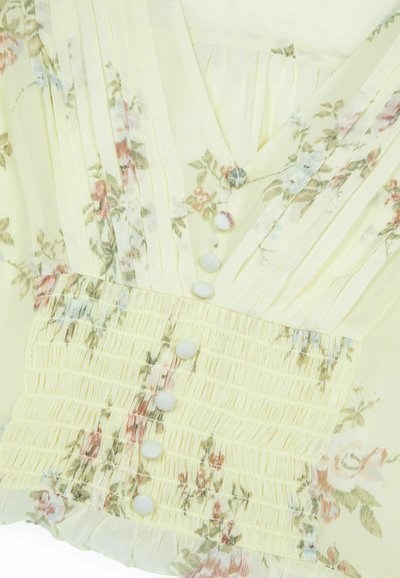 Blusa floreale gialla chiara con pieghe, texture arricciata e bottoni bianchi. Caratterizzata da delicati motivi floreali rosa e blu. Tessuto morbido e trasparente.