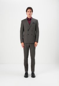 Grey plaid double-breasted suit, featuring a contrasting maroon shirt, black pocket square, and polished black shoes. Tailored fit.