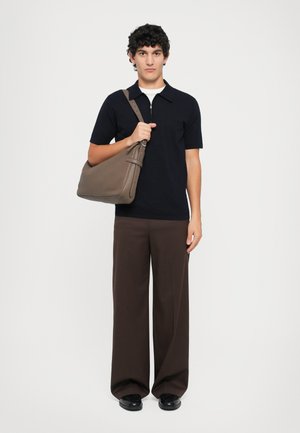 Polo de manga corta en navy, pantalones de pierna ancha marrones y zapatos negros. Sostenido un bolso de hombro marrón con textura suave y correa ajustable.