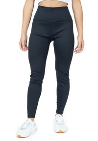 Zwarte hoge taille legging met een gladde textuur, getailleerd ontwerp en rekbare stof, gecombineerd met witte sportschoenen.
