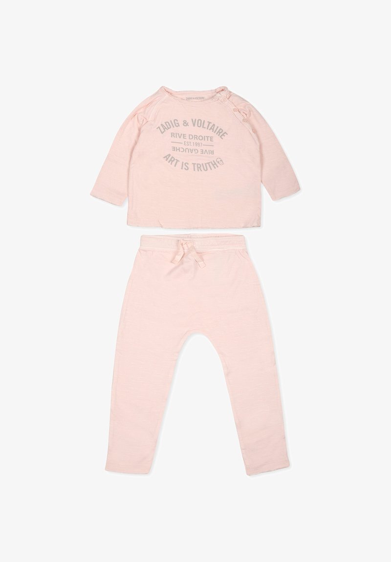 Lichtroze twee-delige outfit met een lang mouwtop met grijze tekst en een broek met een elastische tailleband en trekkoord. Zachte stoftextuur.