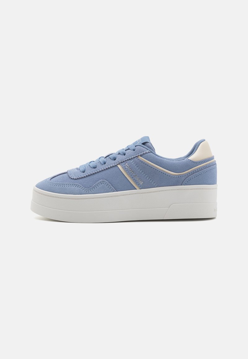 Sneaker blu chiaro con tomaia in tessuto testurizzato, suola piatta bianca e dettagli crema a contrasto lungo il tallone e il lato.