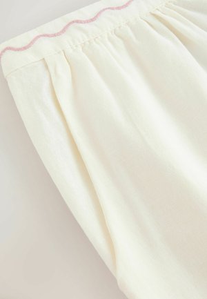 Jasnożółta tkanina o miękkiej fakturze, z plisami i różową falistą lamówką wzdłuż górnej krawędzi.