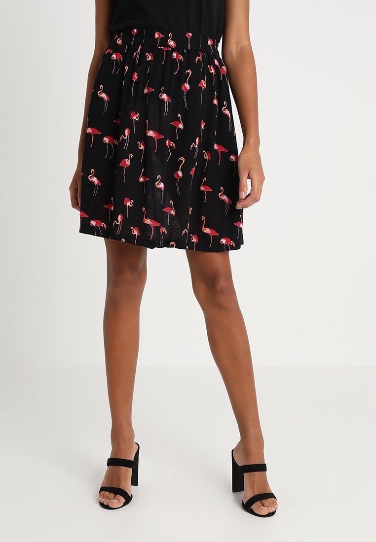 Jupe noire avec une taille élastique froncée, présentant un motif de flamants roses, fabriquée en tissu léger et transparent.