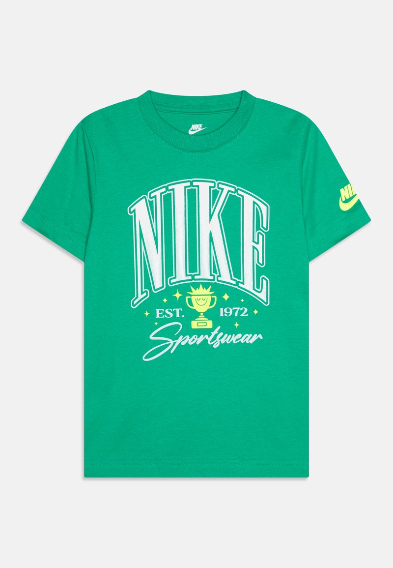 T-shirt de algodão verde com grandes letras brancas "NIKE", um gráfico de troféu e "EST. 1972 Sportswear" em detalhes brancos e amarelos. Mangas curtas.