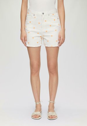 Witte denim shorts met oranje bloemenborduursel, franje aan de onderkant, vijf-pocket ontwerp, gedragen met beige sandaaltjes met banden. Glad oppervlak.