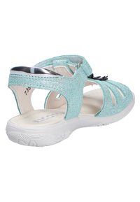 Leicht blauer glitzernder Sandale für Kinder mit weißer Sohle, verstellbarem Knöchelriemen und schwarzer Blumendekoration am vorderen Riemen.