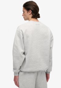 Light gray sweatshirt made of soft cotton blend, featuring a crew neck, long sleeves, ribbed cuffs, and "Superdry" logo at the back.