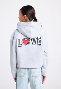 Grijze hoodie met een bedrukte afbeelding waarop "LOVE" staat met een rood hart, op een textuurrijke stof, met een losse pasvorm en capuchon.