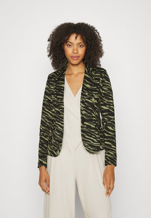 Zeleno-černý pruhovaný blazer s přiléhavým střihem, dlouhými rukávy, klopovými límci a zapínáním na jeden knoflík, kombinovaný s lehkým overalem.
