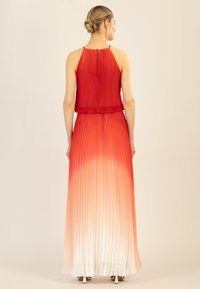 Rotes, plissiertes Maxikleid mit Halterneck, das von Rot zu Weiß verläuft, mit einer taillierten Passform und eleganter Fallbewegung.