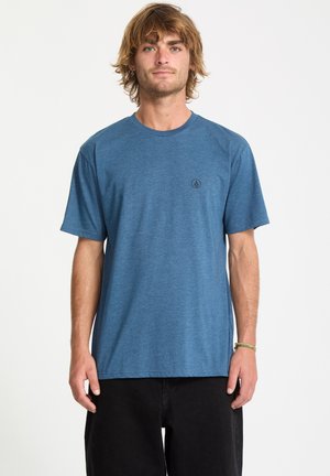 T-shirt bleu à manches courtes en tissu doux, avec un col rond et un petit logo noir sur la poitrine gauche. Coupe décontractée, design minimaliste.