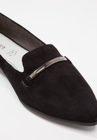 Mocassin pointu en daim noir avec détail en barre métallique argentée sur le dessus et doublure intérieure lisse.