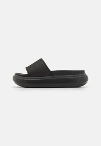 Sandalo scivoloso nero con tomaia morbida e suola in gomma spessa, progettato per il comfort con un profilo minimalista e elegante.